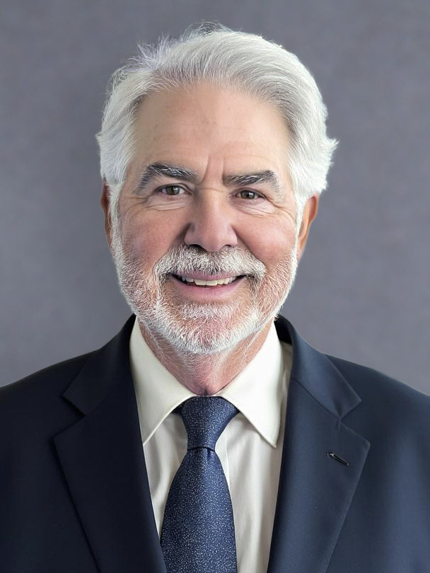a man wearing a suit and tie smiling and looking at the camera